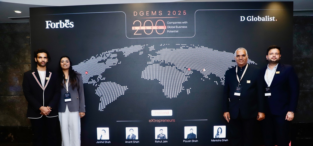 Four people posing infront of a large banner for DGEMS 2025